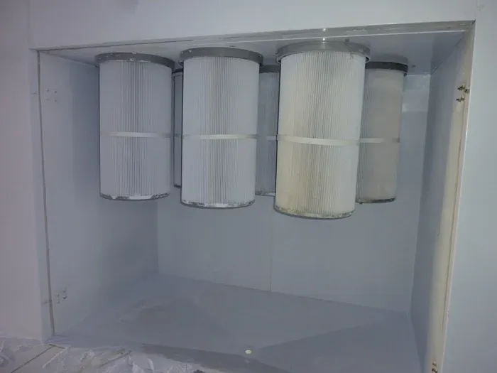 Cartridge powder recovery house beside a powder spray booth